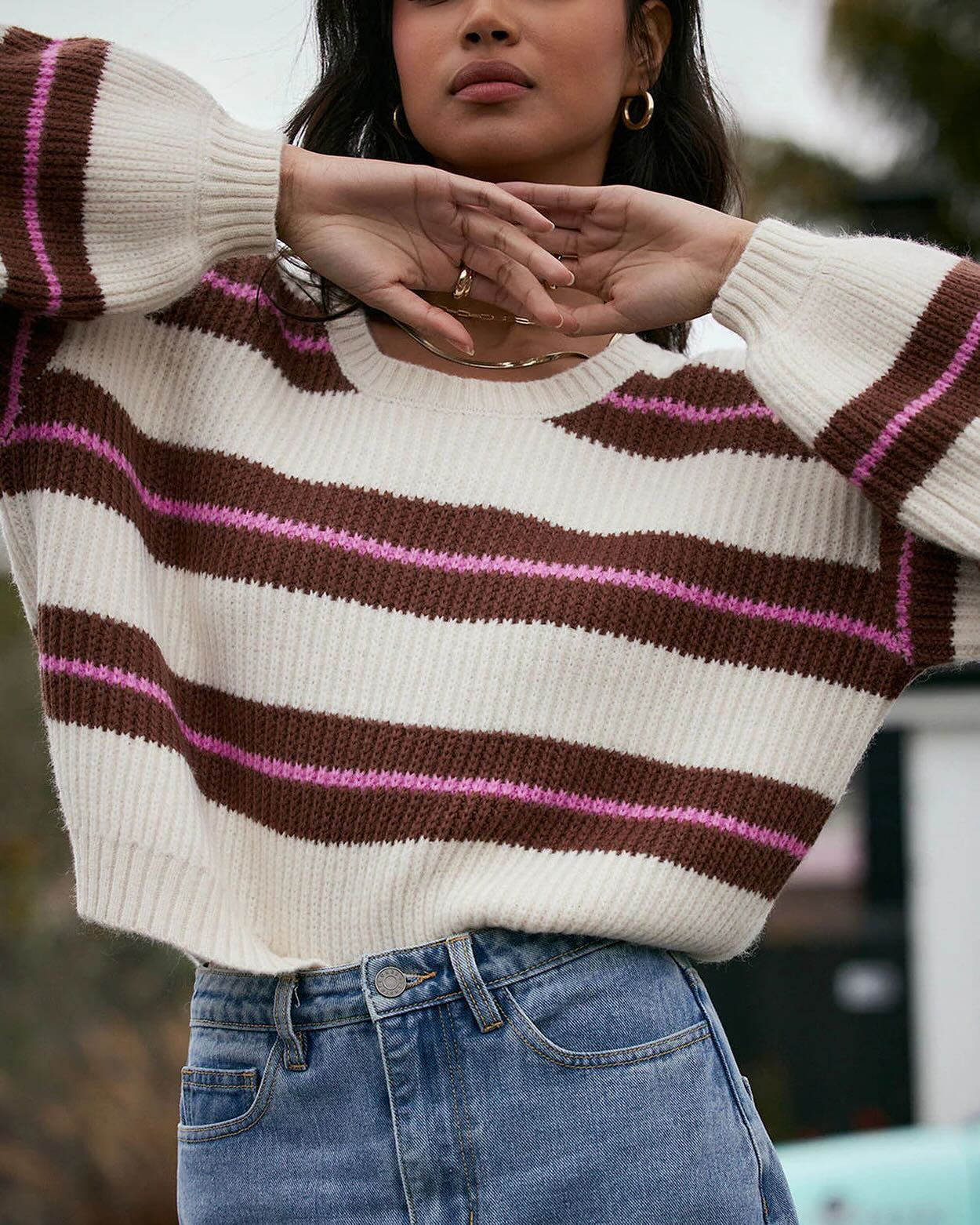 a model in a striped sweater and jeans posing